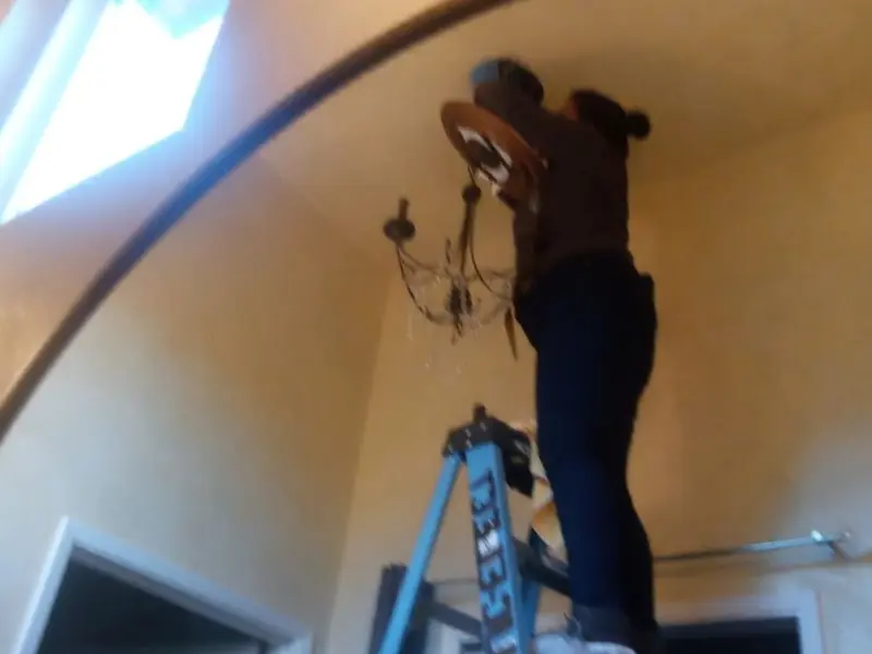 Electrician installing a chandelier in a Carmel-by-the-Sea residence